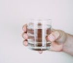 A close-up shot of a hand holding a clear glass of water, symbolizing refreshment.